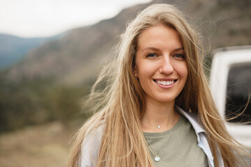 Portrait of happy young caucasian girl posing near off-road car