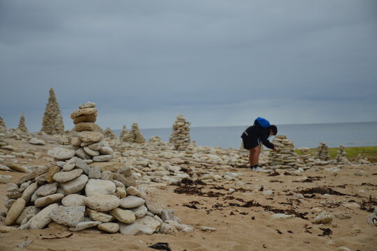 Boy building his own meditation tower by the sea