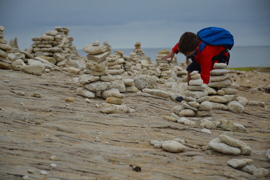 Boy building his own meditation tower by the sea
