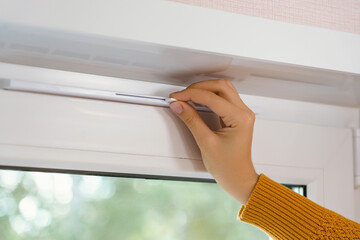 Supply ventilation on a plastic window, a woman's hand in a yellow sweater moves the ventilation...
