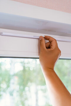 Supply ventilation on a plastic window, a man's hand moves the ventilation lever on the window. Vertical photo