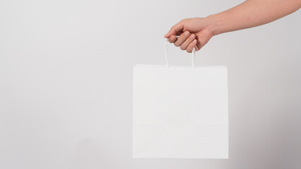 Hand is hold white shopping bag isolated on white background.