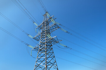 High-voltage power line support on a blue sky background, bottom view.