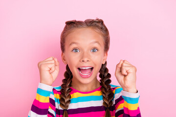 Photo of astonished funky little lady raise fists celebrate victory wear striped shirt isolated pink color background