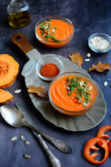 Vertical autumn composition. Bright pumpkin soup, peppers, spices on a gray background.