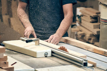 A carpenter works on a circular saw in his workshop.