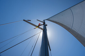 Mast of sail boat with white sails