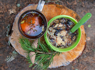 Camping lunch porridge with mushrooms and herbal tea cooked over a campfire. - 457157563
