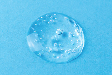 Gel drop with bubbles on blue background. Antibacterial gel or facial serum closeup. Transparent...