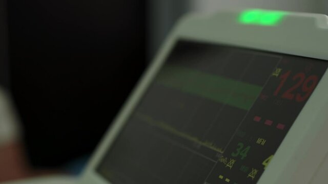 Electronic Cardiotocography Machine Monitoring Fetal Heart Contractions Of Uterus. Printing Cardiogram Report Coming Out Electrocardiogram In Labor Ward During Pregnancy. Medical Diagnostic Equipment