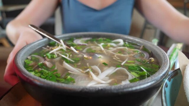 close-up of a plate, someone eating pho bo soup.