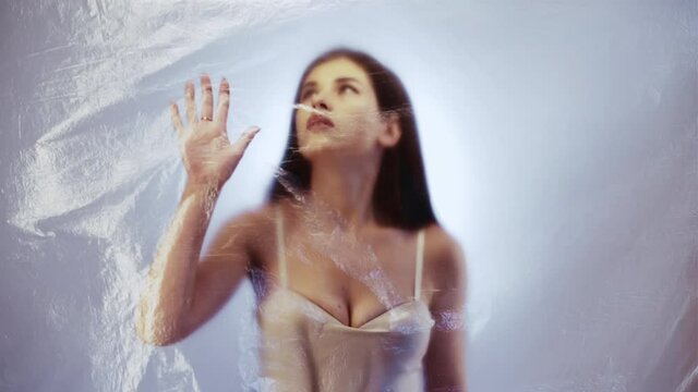 Female rights. Woman loneliness. Sexism problem. Isolation abandonment. Defocused trapped depressed victim silhouette hands against plastic wrap on light out of focus background.