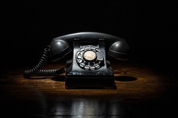 Antique Vintage Black Timey Old Rotary Phone in Dark Contrasty Moody Light Overhead Spot Light on...