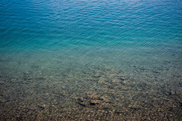 Pebbles and clear blue water of a lake