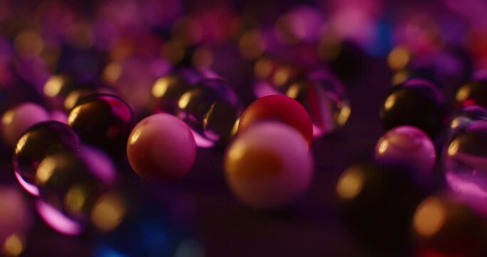 Multicolored marbles lying on black surface. Tracking shot, abstract background. 