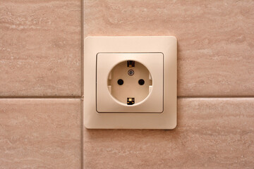 Electric socket on a tiled wall, close-up