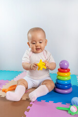Happy toddler child playing with yellow rubber toy on colorful puzzle mat