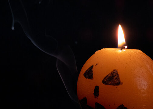 halloween orange candle lit with smoke and black background