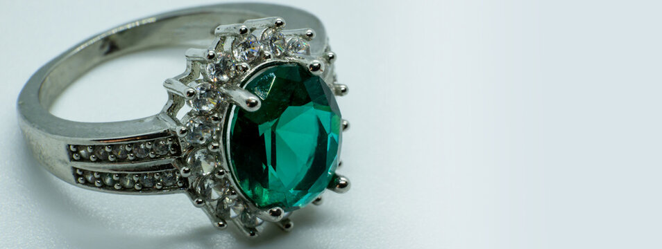 banner ring with precious stone, emerald gem set. white background