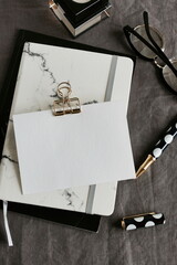 Blank paper mockup, notepads, pen, glasses top view on gray linen tablecloth with copy space. Home workspace concept.