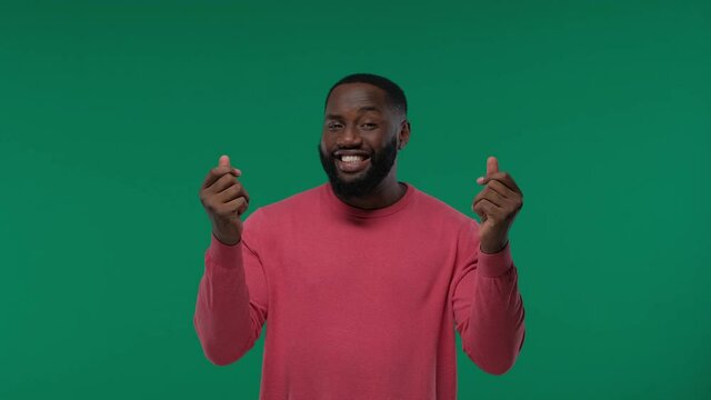 Smiling young african american guy in casual posing isolated on Green Screen background. Rubbing fingers showing cash gesture asking for money