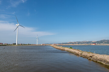 Coastline wind turbine under blue sky
