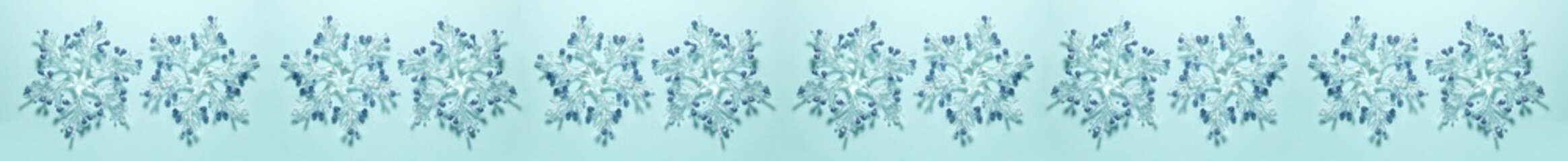 Banner of transparent snowflakes with golden glitters at the tips on a bright blue background. Christmas concept lat lay top view