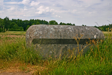 Stojący pośród pól lekki betonowy polski schron bunkier