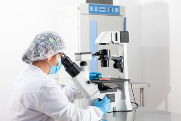 Young female scientist looking at samples under the microscope