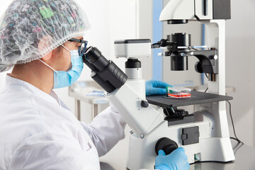 Young female scientist looking at samples under the microscope