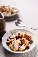 Not traditional Eton mess. Meringue, pistachio, cherry and caramel sauce dessert. Selective focus