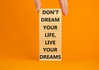Live your dreams symbol. Wooden blocks with words Do not dream your life, live your dreams. Beautiful orange background. Businessman hand. Business and live your dreams concept. Copy space.