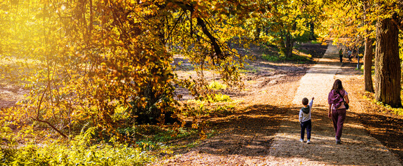 mom and son are walking in the park in the fall