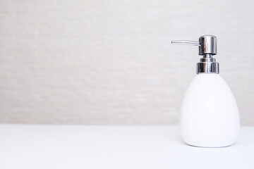 White liquid soap, body lotion dispenser on light background of bathroom with copy space