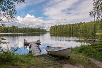 idyllischer Ausblick auf einen See mit Boot und Holzsteg