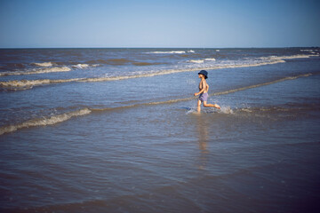 Fototapeta na wymiar boy child in striped swimming trunks runs around the sea near the beach