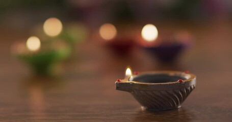 Lit candles in decorative clay pots on wooden table top, focus on foreground one, bokeh background - Powered by Adobe