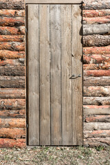 A closed wooden door in an old log barn. Rural lifestyle.