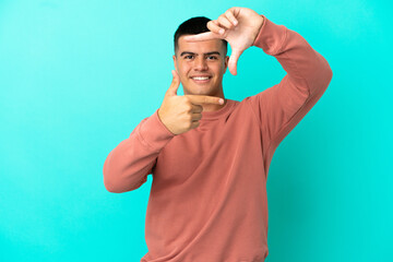 Naklejka premium Young handsome man over isolated blue background focusing face. Framing symbol