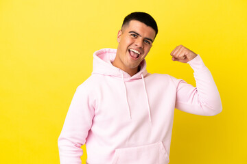 Young handsome man over isolated yellow background doing strong gesture