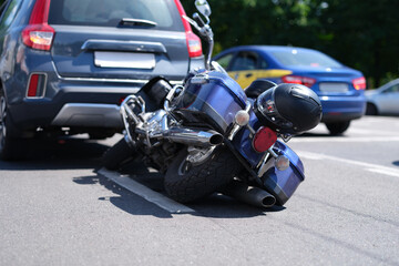 Blue motorcycle lying on road near car closeup