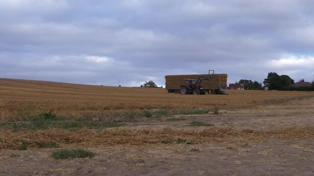 Tractor and hay bales after harvest wide shot - Powered by Adobe