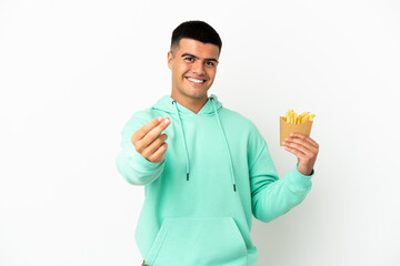 Young handsome man holding fried chips over isolated white background making money gesture