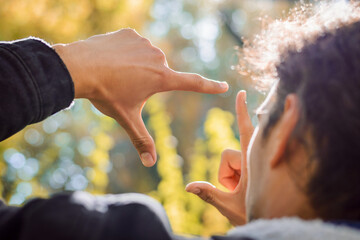 Young male student photographer found nice composition for a shot in bright autumn forest showing...