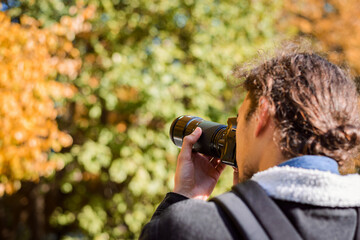 Back photo of photographer shooting autumn park. Concept of depicting fall season on photos