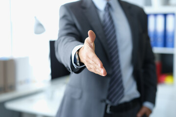 Man in business suit stretching out his hand for handshake closeup