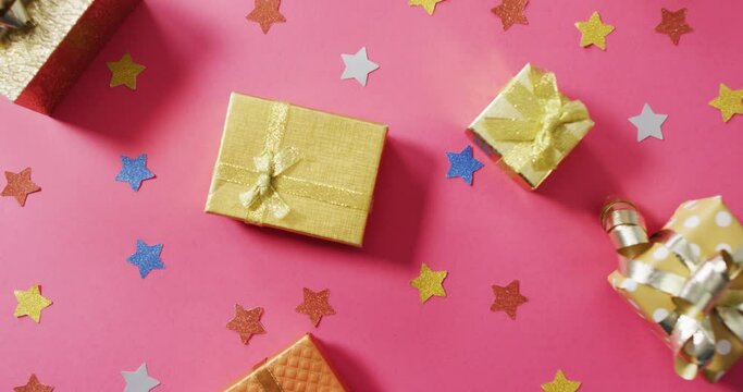Video of wrapped presents and colourful stars on pink background