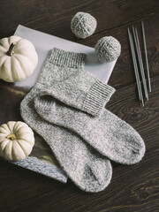 Hand knitting socks with needles and yarn balls on a dark wooden background.  Concept for handmade and hygge slow life.