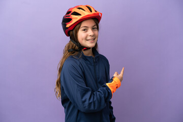 Little caucasian girl isolated on purple background pointing back