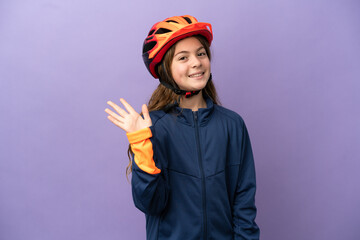 Little caucasian girl isolated on purple background saluting with hand with happy expression